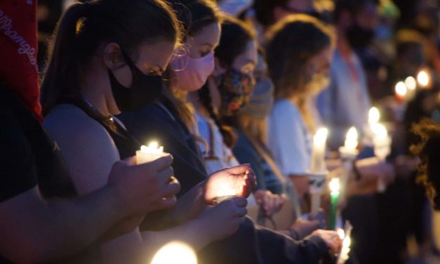 Demonstrators pause outside police headquarters to hold “Black Lives Matter” candlelight vigil